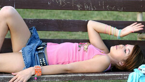 Charming young and fresh girl flashes her white panties on the bench in the park