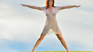 One sexy redhead takes off her dress while near a lake