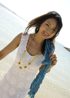Sweet Japanese girl in white dress walks into the water being dressed