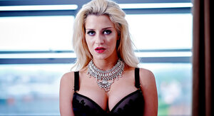 Blonde adult star in black lingerie looks into the camera and additionally takes boobs out