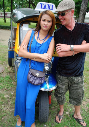 Hot dame from Thailand poses in her slinky blue dress by a small taxi