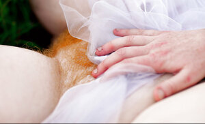 Super-pale ginger lays on the green grass and also poses absolutely nude