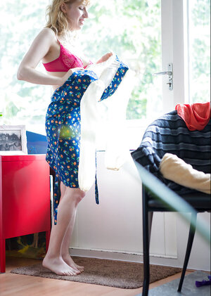 18-19 year old in red bra and green panties wears a blue dress in front of a huge window