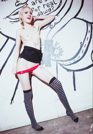 Small-tittied slim girl in striped over-the-knee socks poses by graffiti wall